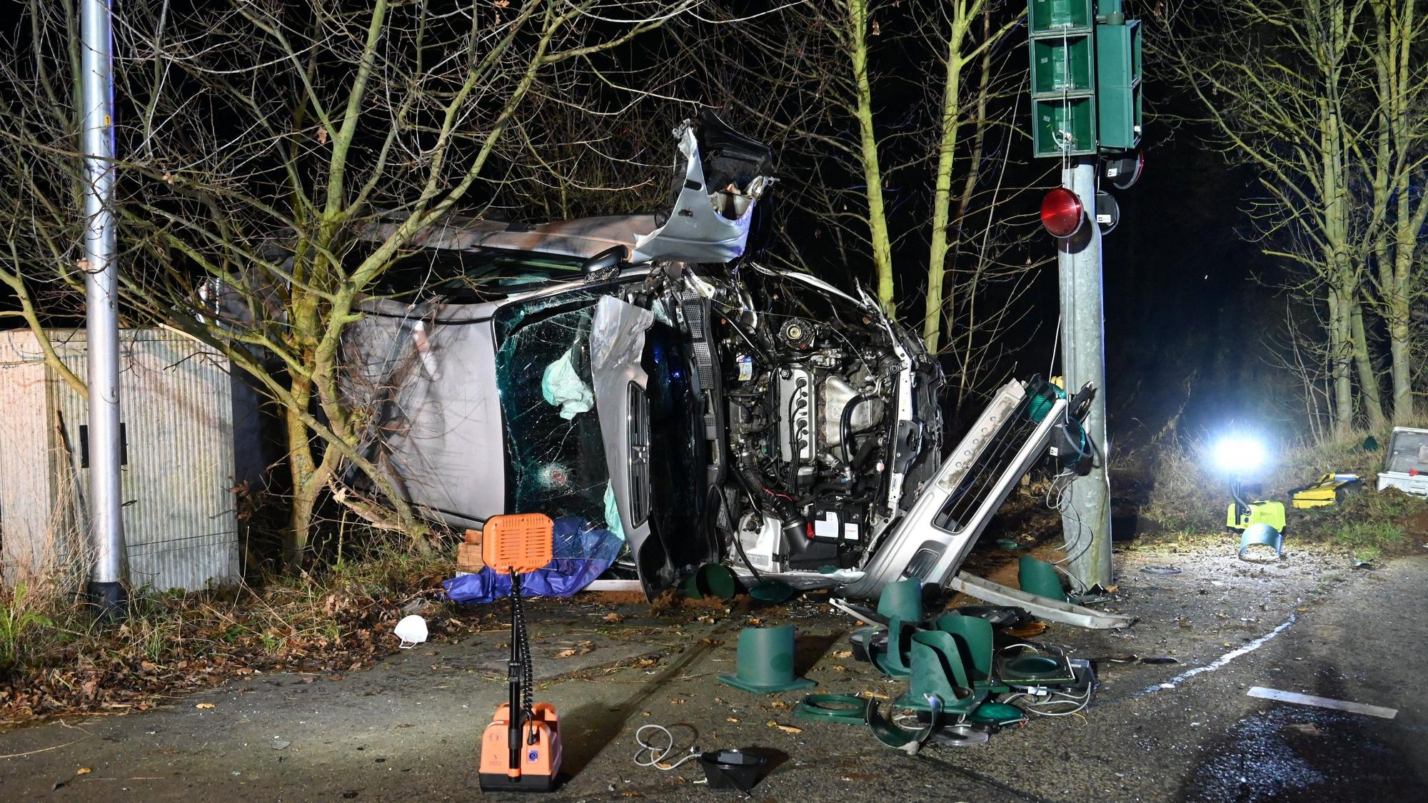 Ein zerstörtes Auto liegt an einem Baum.