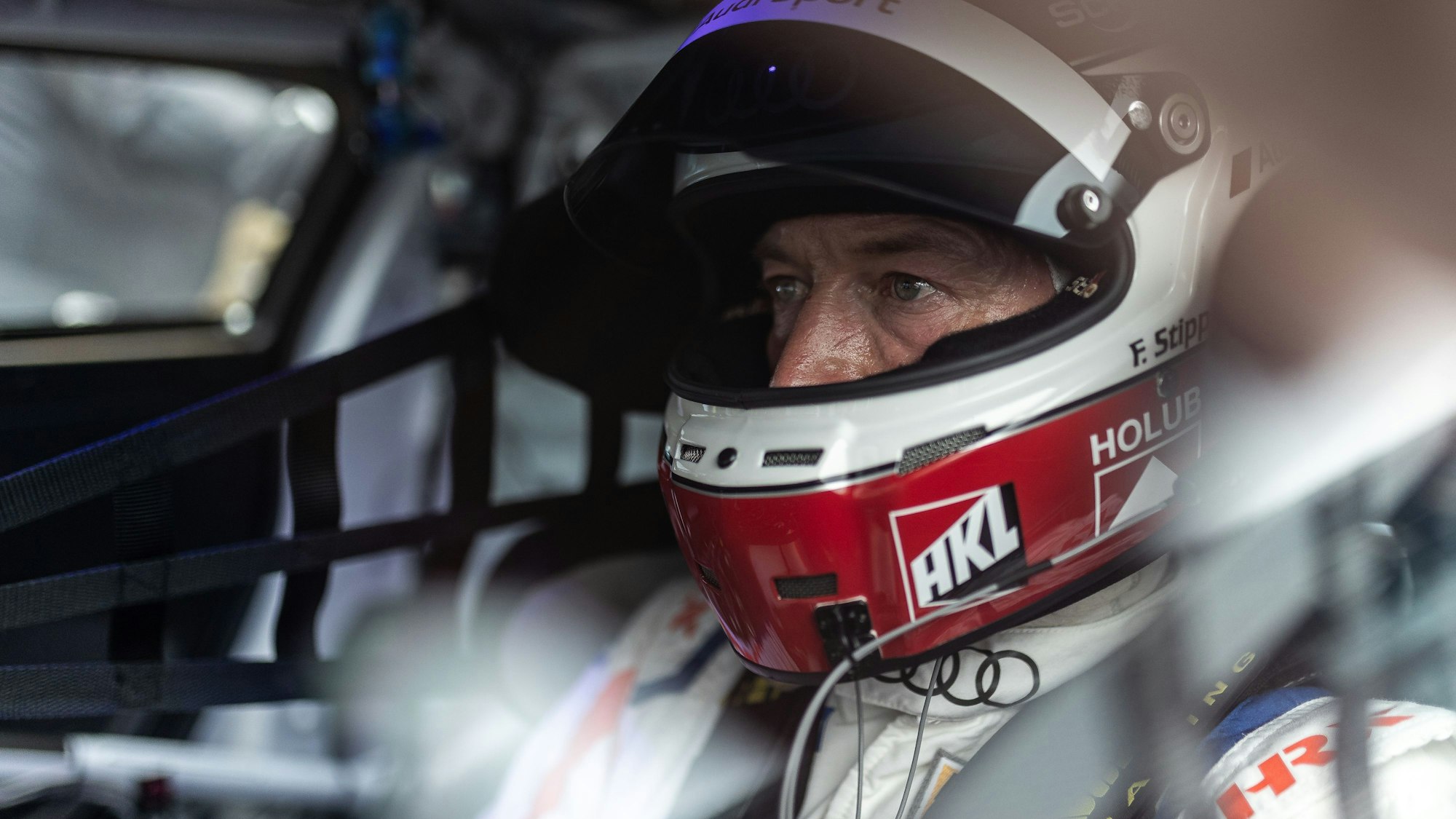 Das Bild zeigt Frank Stippler in einem Rennauto sitzend. Er trägt einen Helm.