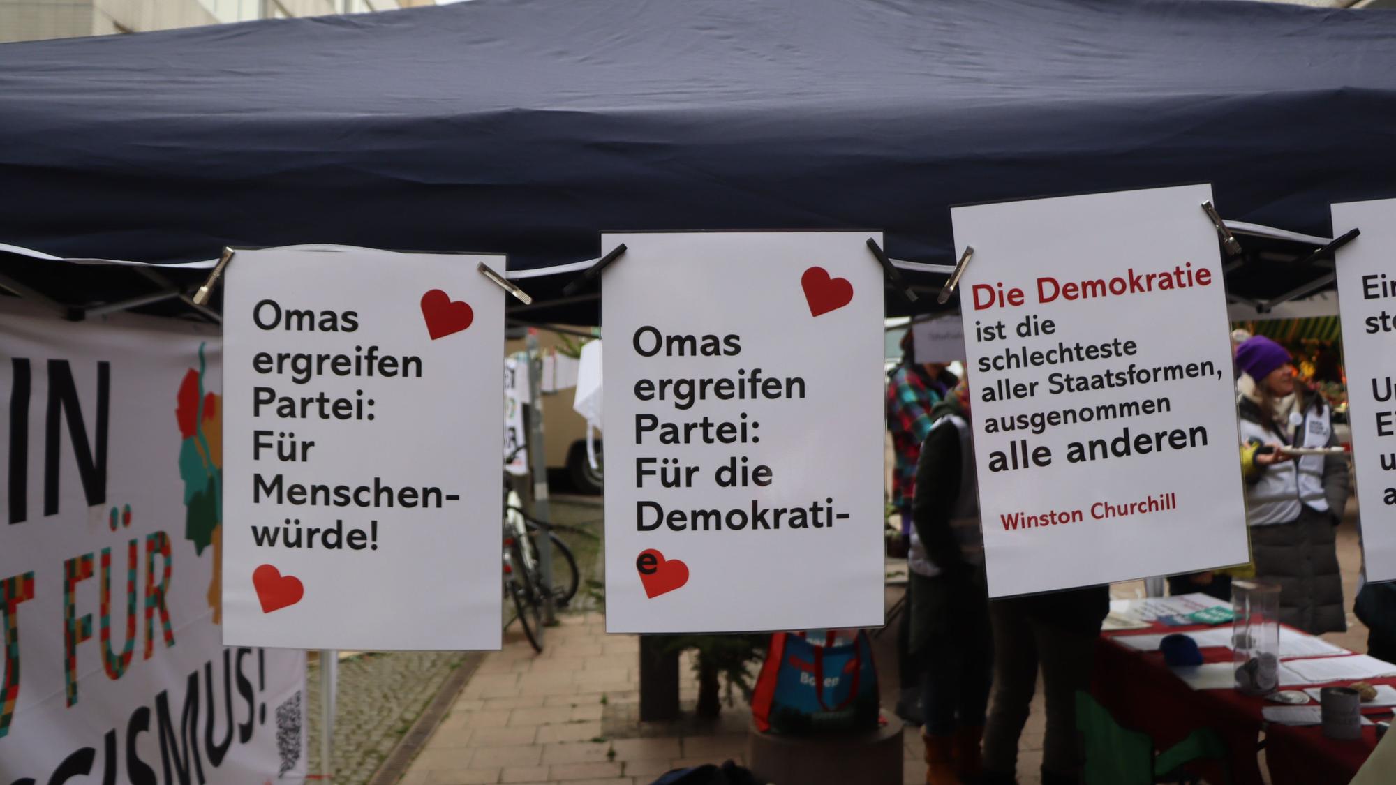 Das Foto zeigt aufgehängte Plakate an einem Infostand.