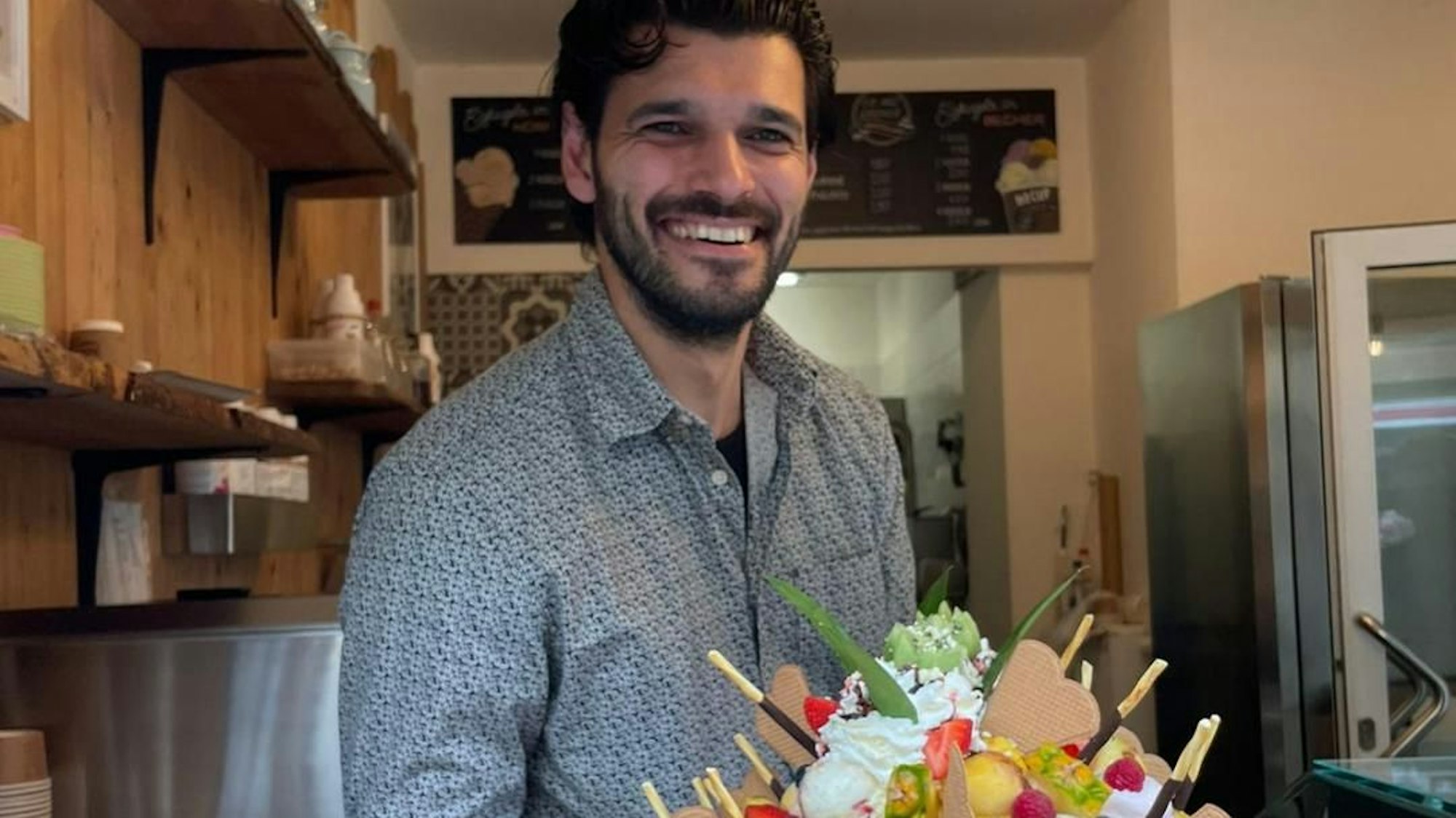 Ein Mann hält einen großen Eisbecher.