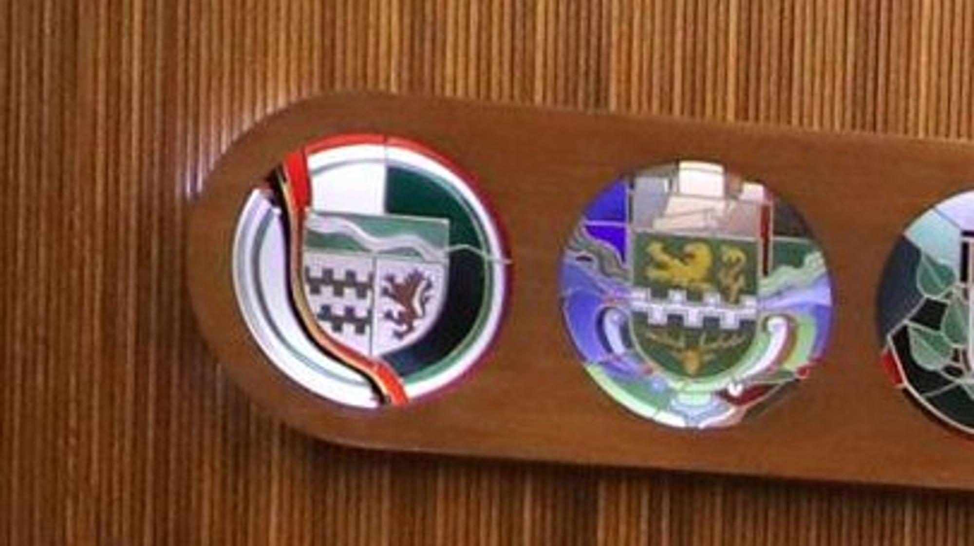 An der Wand des großen Sitzungssaals im Kreishaus Am Rübezahlwald in Bergisch Gladbach hängen Wappen von Kreis und kreisangehörigen Kommunen.