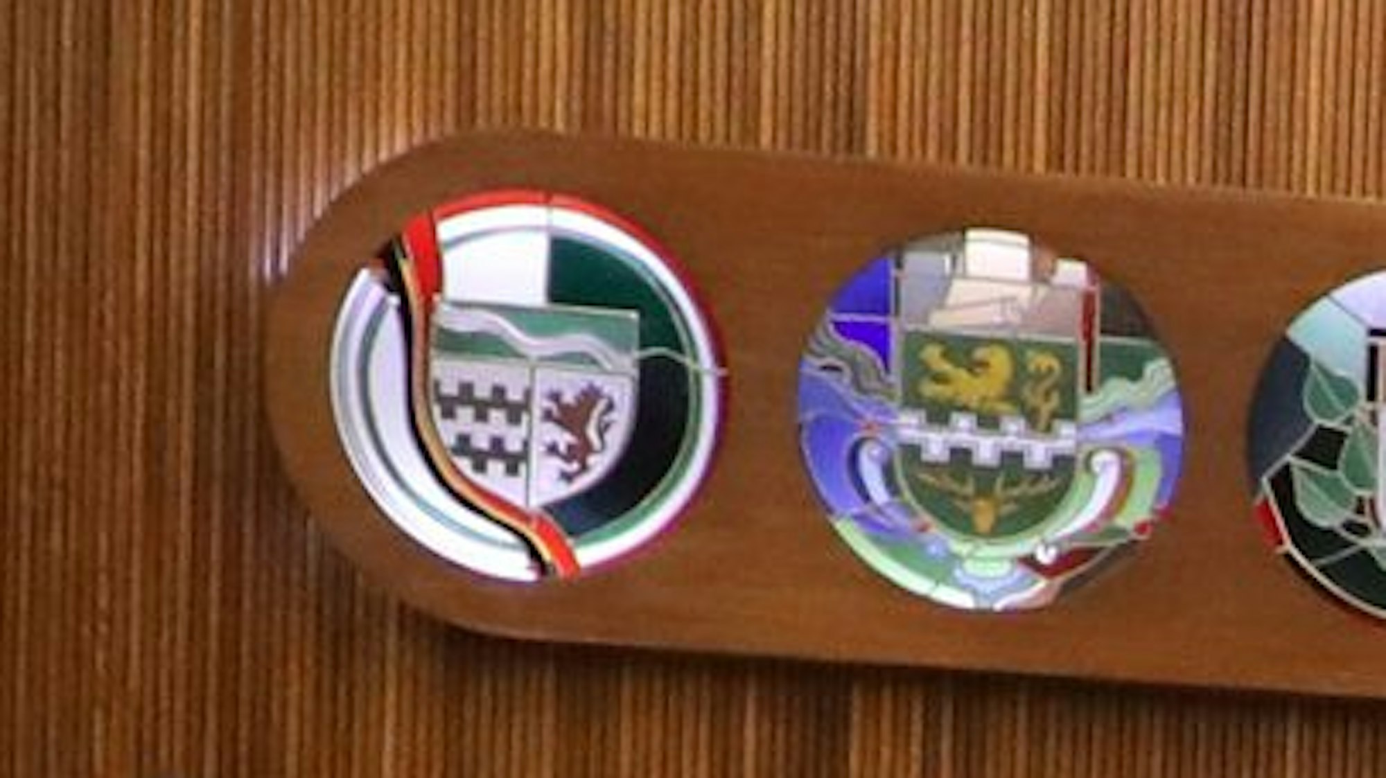 An der Wand des großen Sitzungssaals im Kreishaus Am Rübezahlwald in Bergisch Gladbach hängen Wappen von Kreis und kreisangehörigen Kommunen.