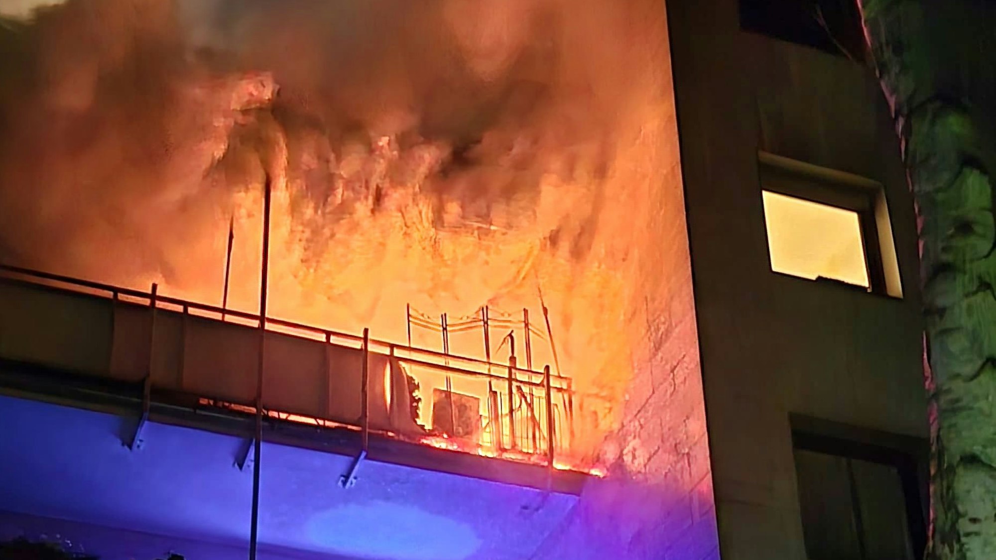 Das Bild zeigt hohe Flammen, die von einem Balkon gegen die Hausfassade schlagen.