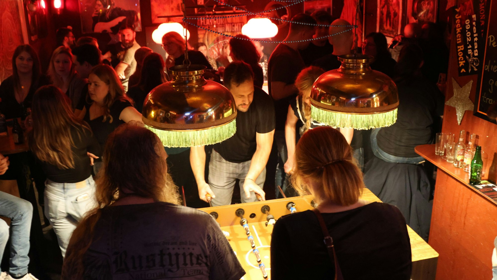 Blick auf Menschen, die an einem Kickertisch spielen.