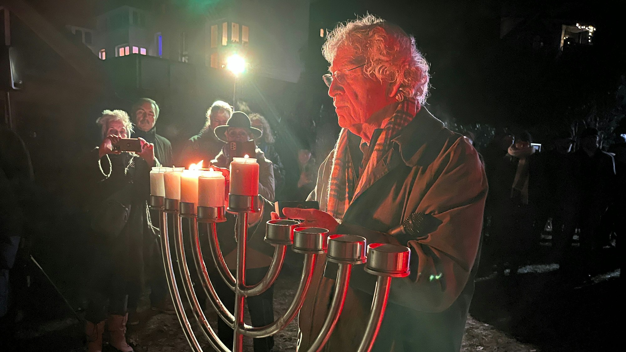 Ein Mann steckt Kerzen an einem Leuchter an.