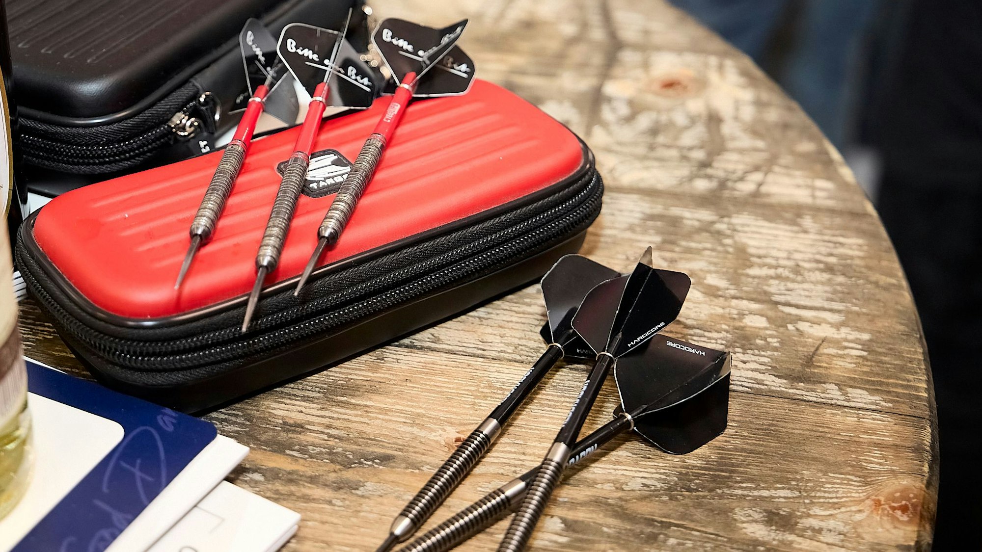 Sechs Dartpfeile liegen auf einem Holztisch.