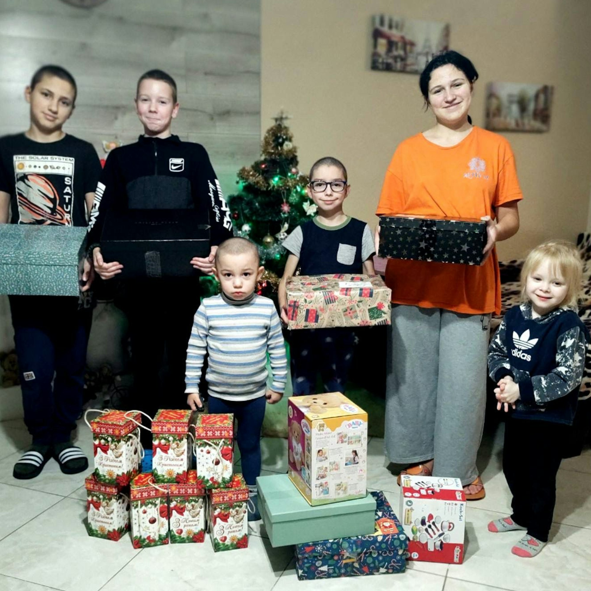 Kinder stehen mit Geschenken im Wohnzimmer einer Waisen-Familie im ukrainische Butscha.