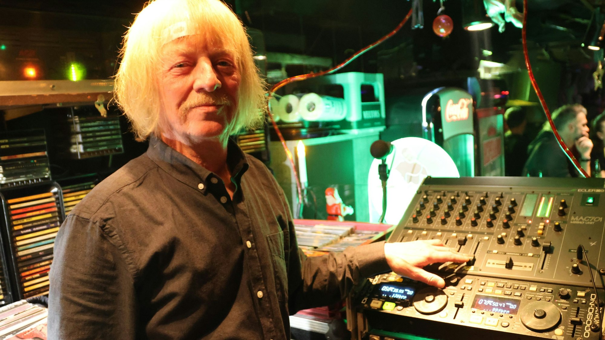 Zu sehen ist ein älterer DJ an einem Mischpult.