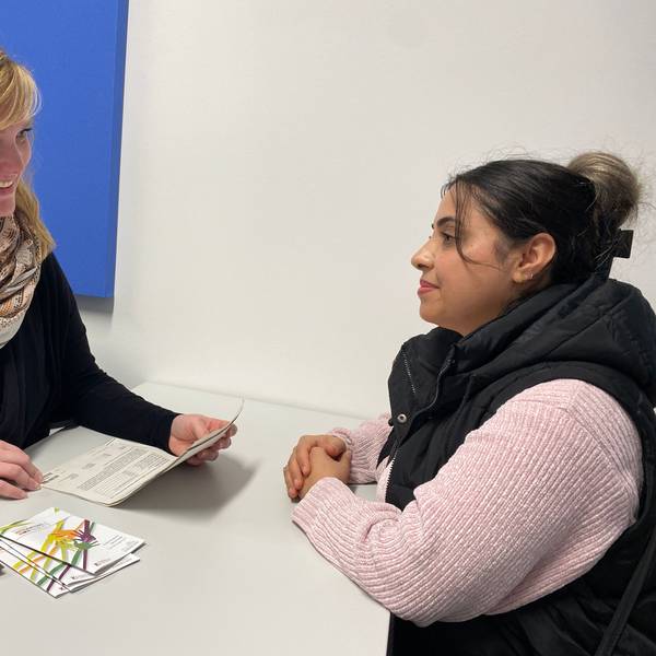 Nora Habeth-Baumgarten und Elmaz Arab sitzen sich gegenüber. Papiere und Broschüren liegen zwischen ihnen auf einem Tisch.