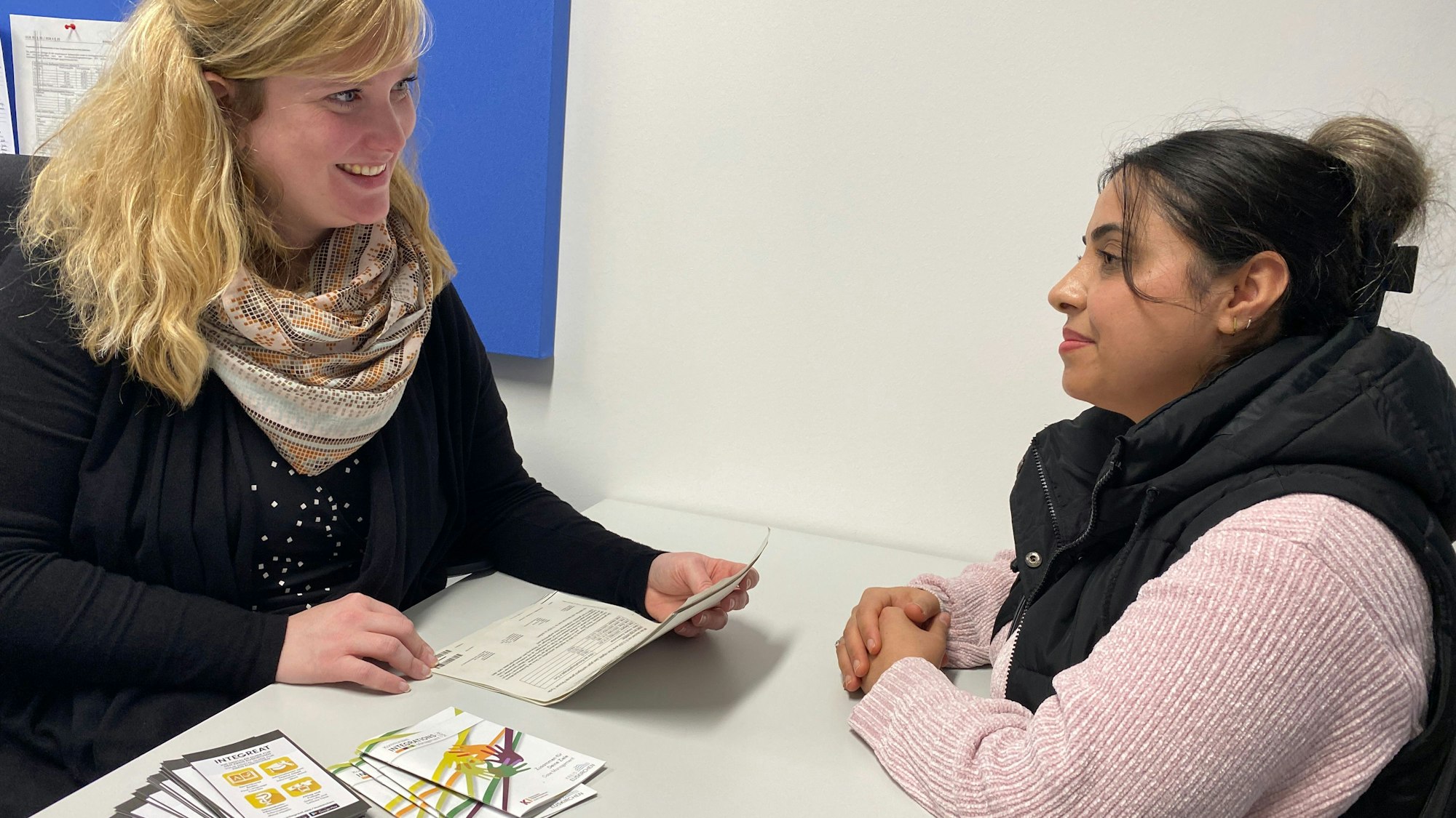 Nora Habeth-Baumgarten und Elmaz Arab sitzen sich gegenüber. Papiere und Broschüren liegen zwischen ihnen auf einem Tisch.