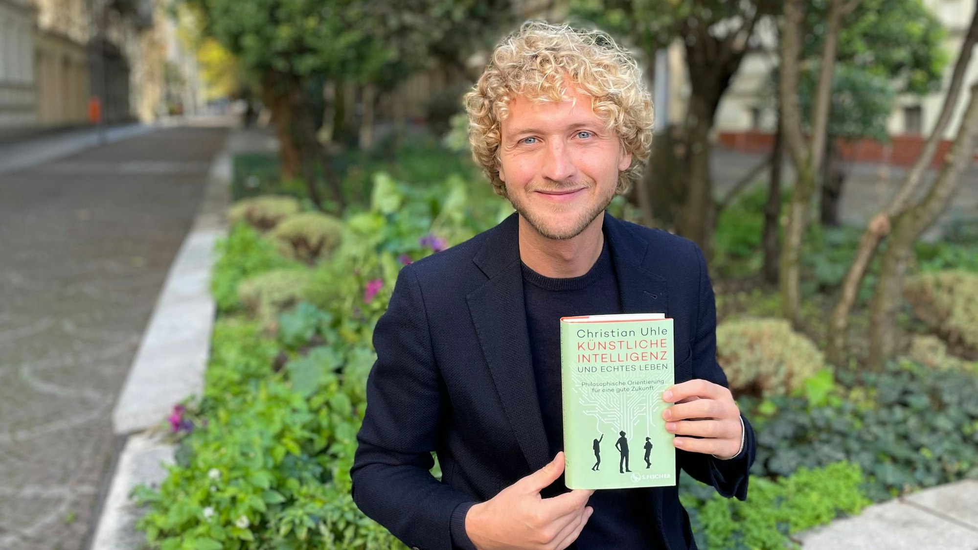 Auf dem Bild ist ein Mann, Christian Uhle, mit seinem neuen Buch zu sehen.