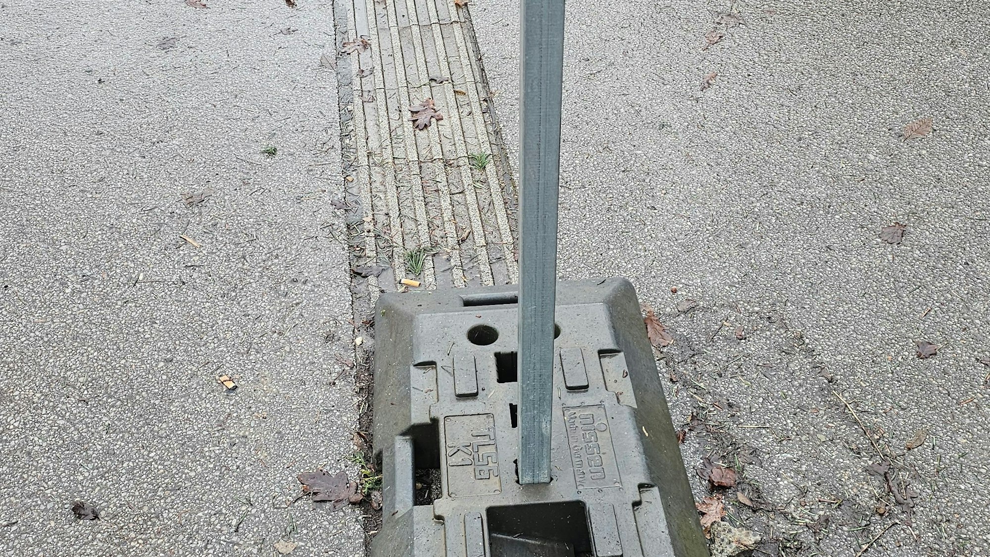 Auf dem Markierungsstreifen für Blinde steht der Fuß des Verkehrsschildes.