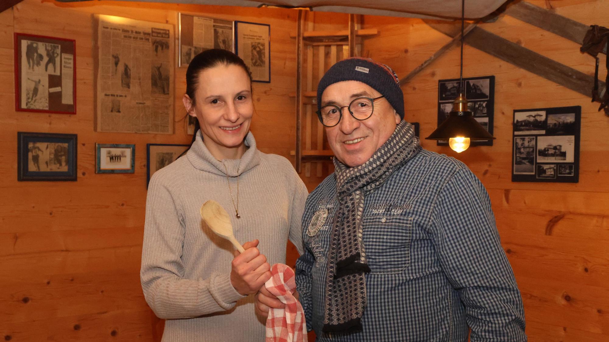 Eine Frau nimmt einen großen, hölzernen Kochlöffel von einem Mann