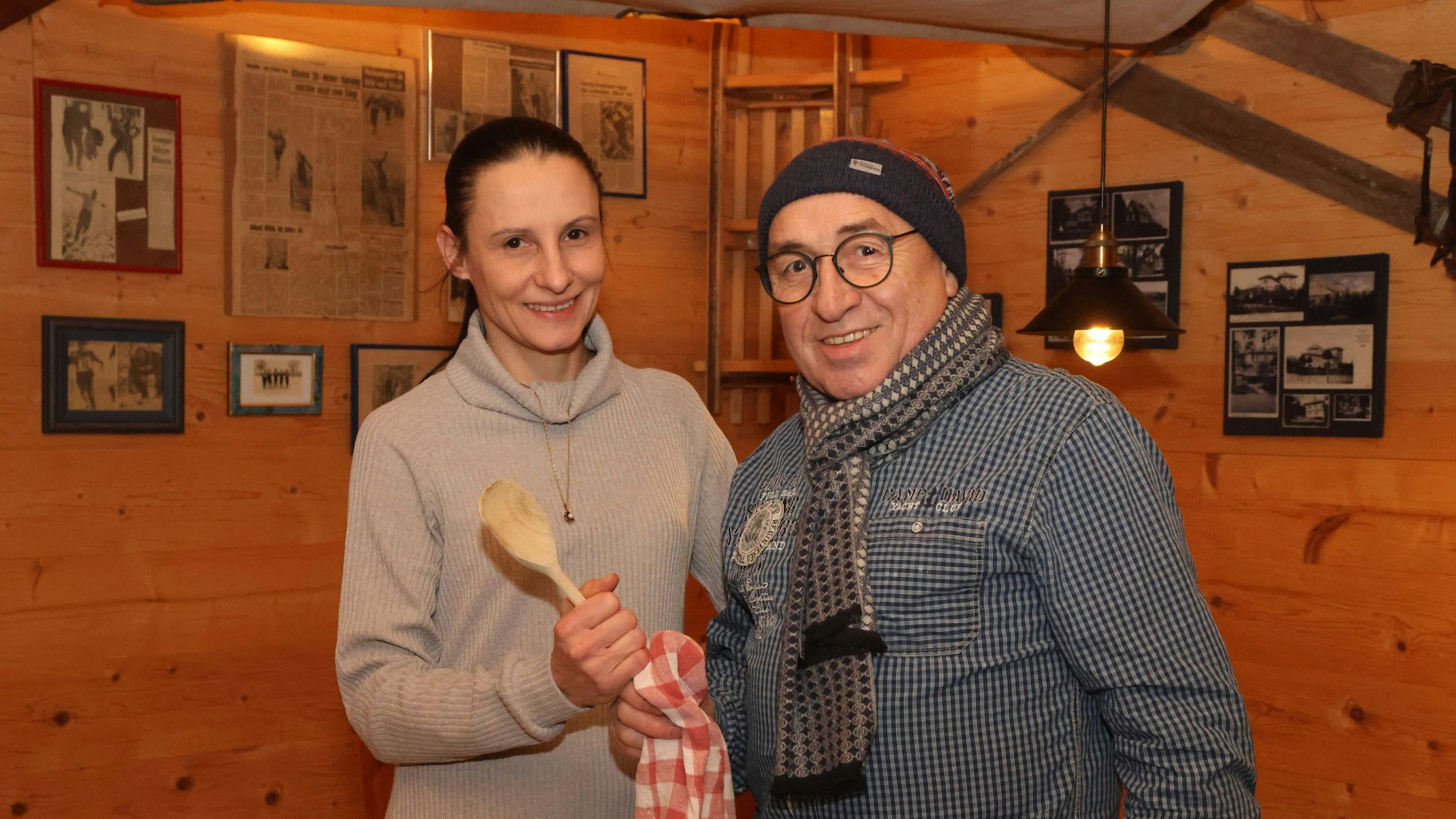 Eine Frau nimmt einen großen, hölzernen Kochlöffel von einem Mann