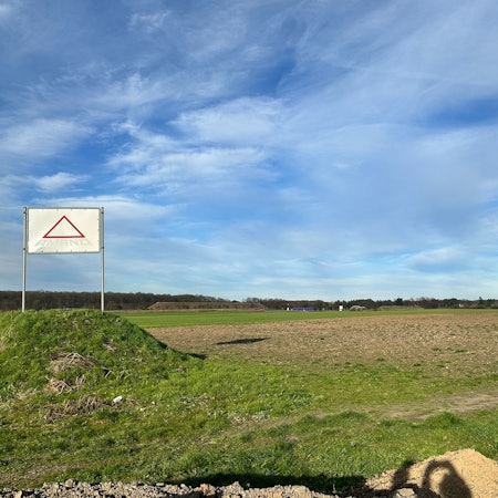 Ein grün-braunes Feld und blauer Himmel.