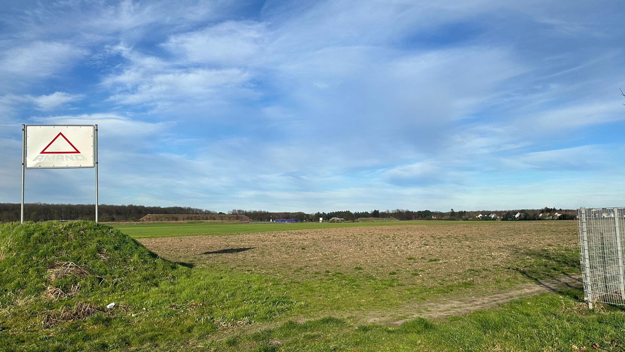 Ein grün-braunes Feld und blauer Himmel.