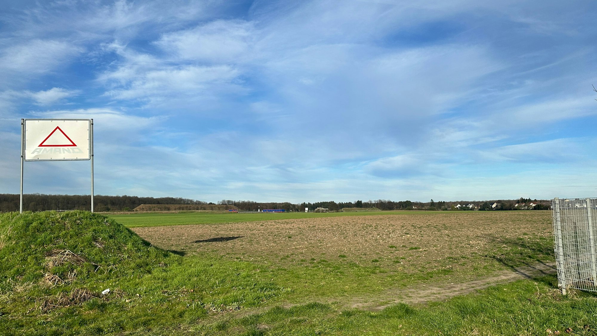 Ein grün-braunes Feld und blauer Himmel.