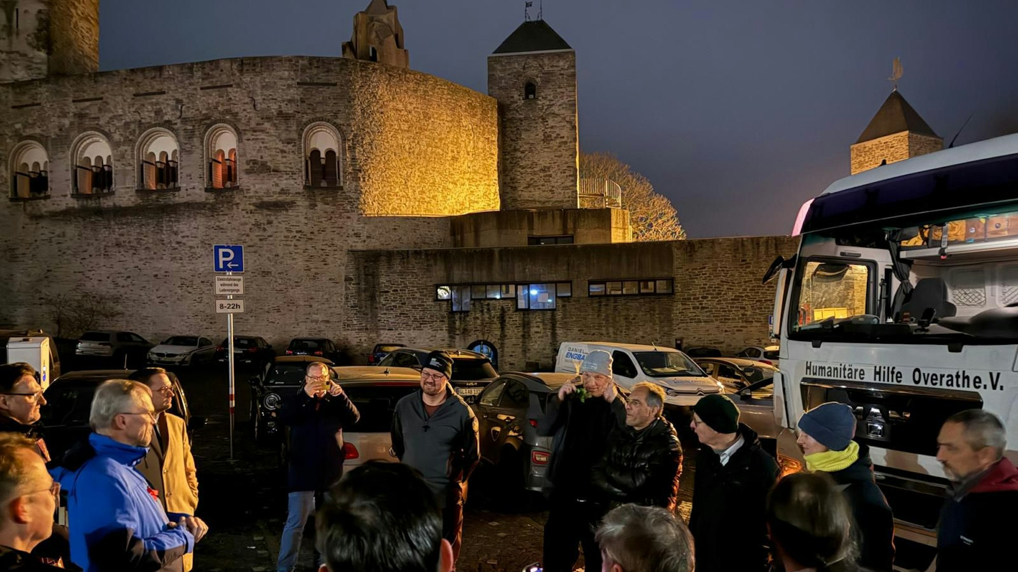 Eine Gruppe von Männern steht vor einem Lkw der Humanitären Hilfe Overath.