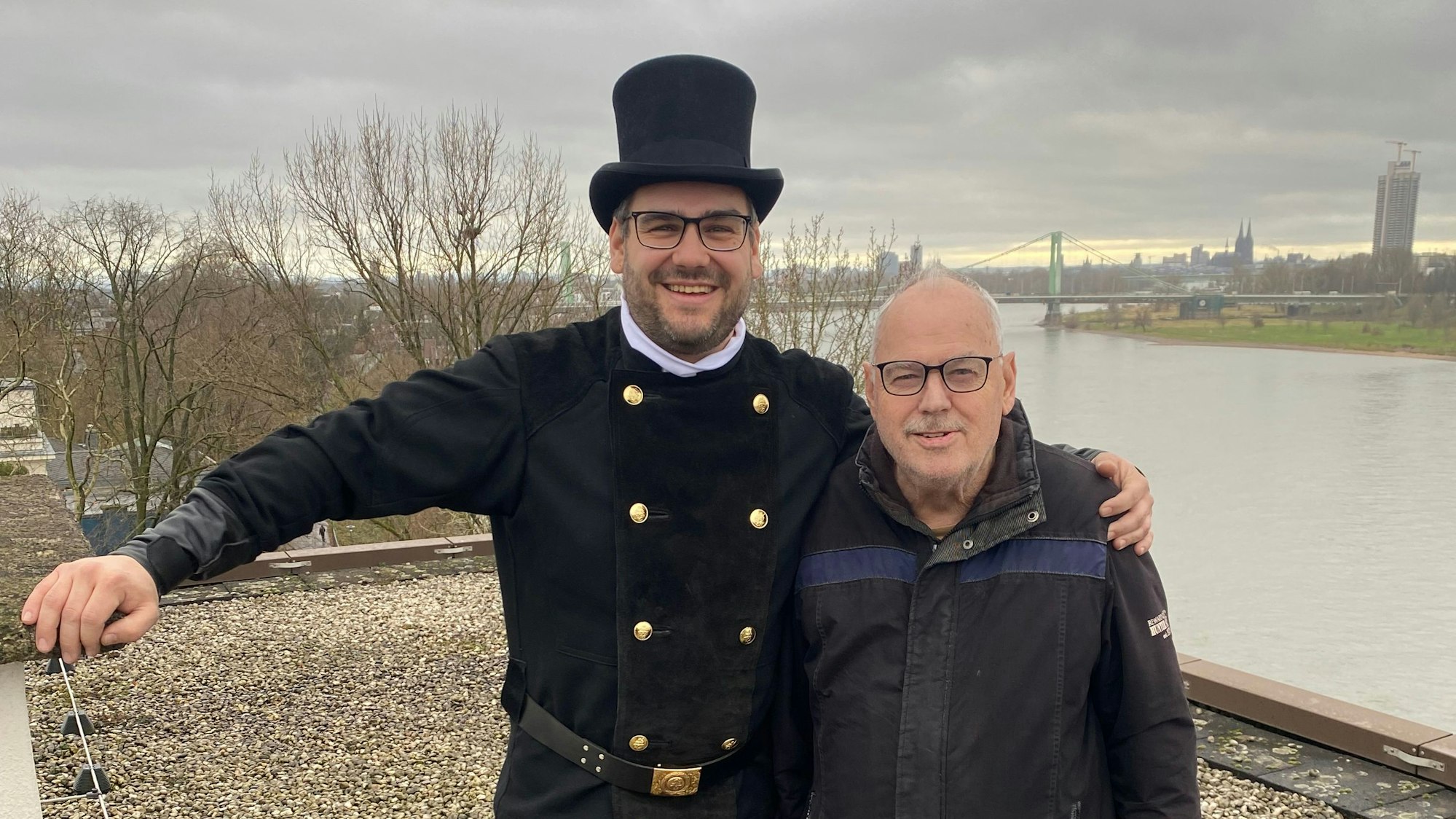 Ein junger Schornsteinfeger umarmt einen älteren Mann.