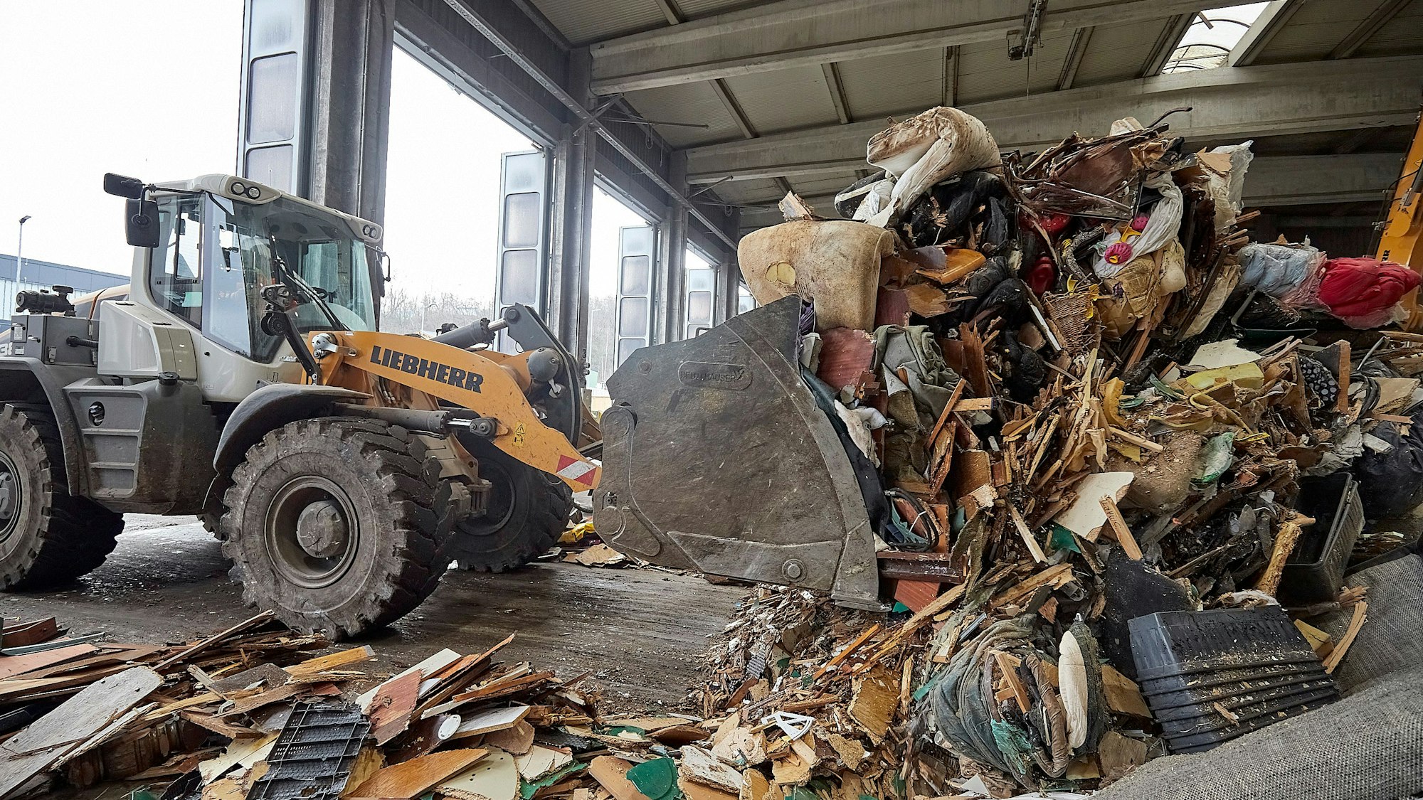Das Bild zeigt einen Bagger, der im Abfallwirtschaftszentrum des Kreises Sperrmüll aufschüttet.
