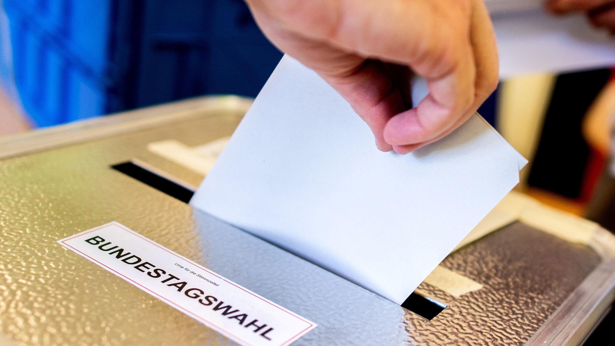 Ein Wähler wirft in einem Wahllokal seinen Stimmzettel für die Bundestagswahl in eine Wahlurne (Symbolbild).