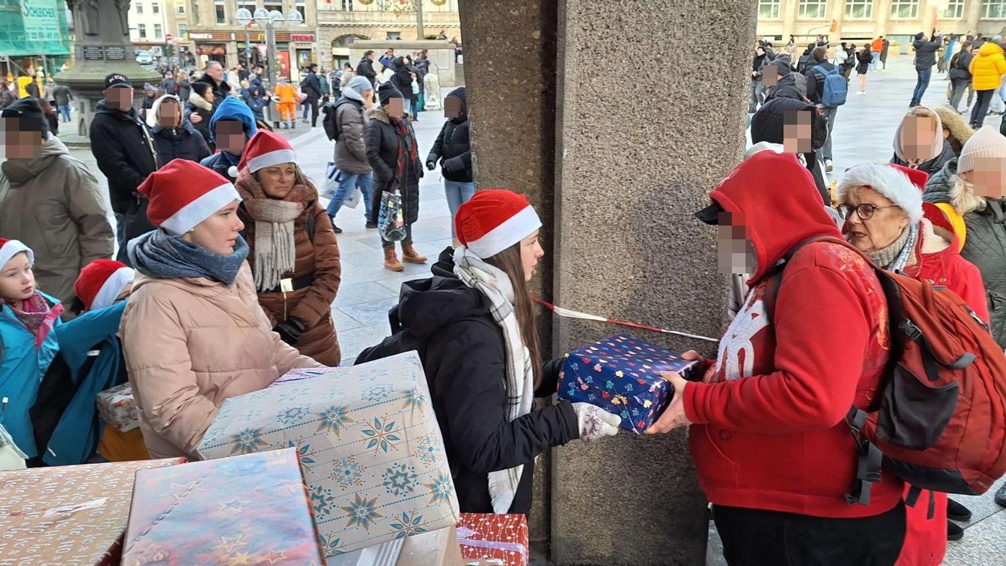Kinder, die Weihnachtsmützen tragen, übergeben Bedürftigen Geschenke.