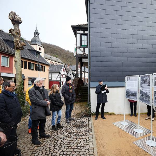 Einige Menschen stehen in Heimbach vor Stellwänden, auf denen alte Fotos zu sehen sind.