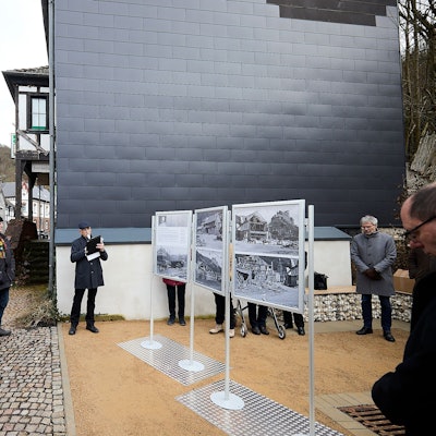 Einige Menschen stehen in Heimbach vor Stellwänden, auf denen alte Fotos zu sehen sind.