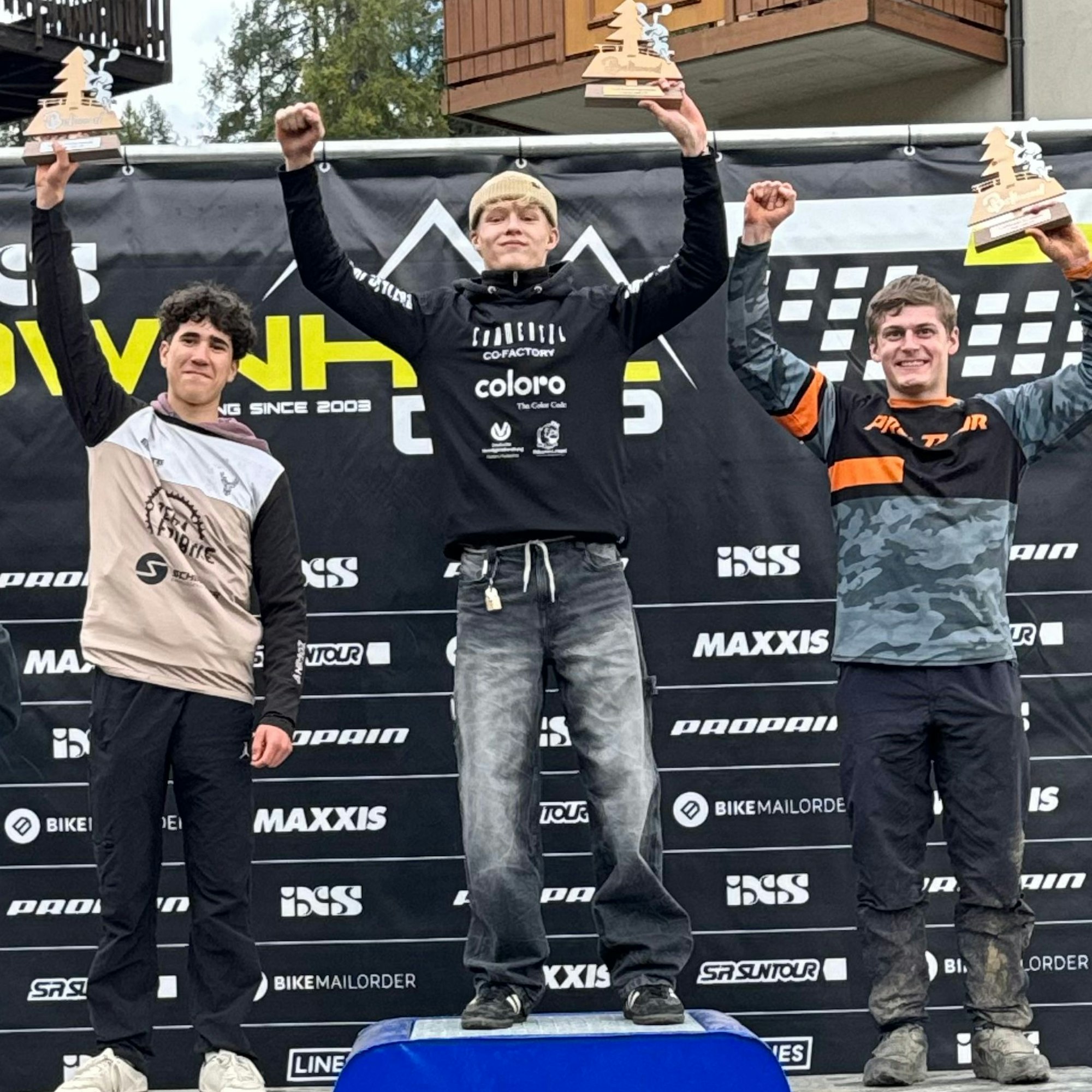 Julian Hundt steht mit einem Pokal in der Mitte vom Siegertreppchen.