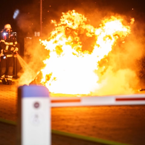 Die Feuerwehr gibt mit einem Feuerwehrschlauch Wasser auf ein Feuer ab.