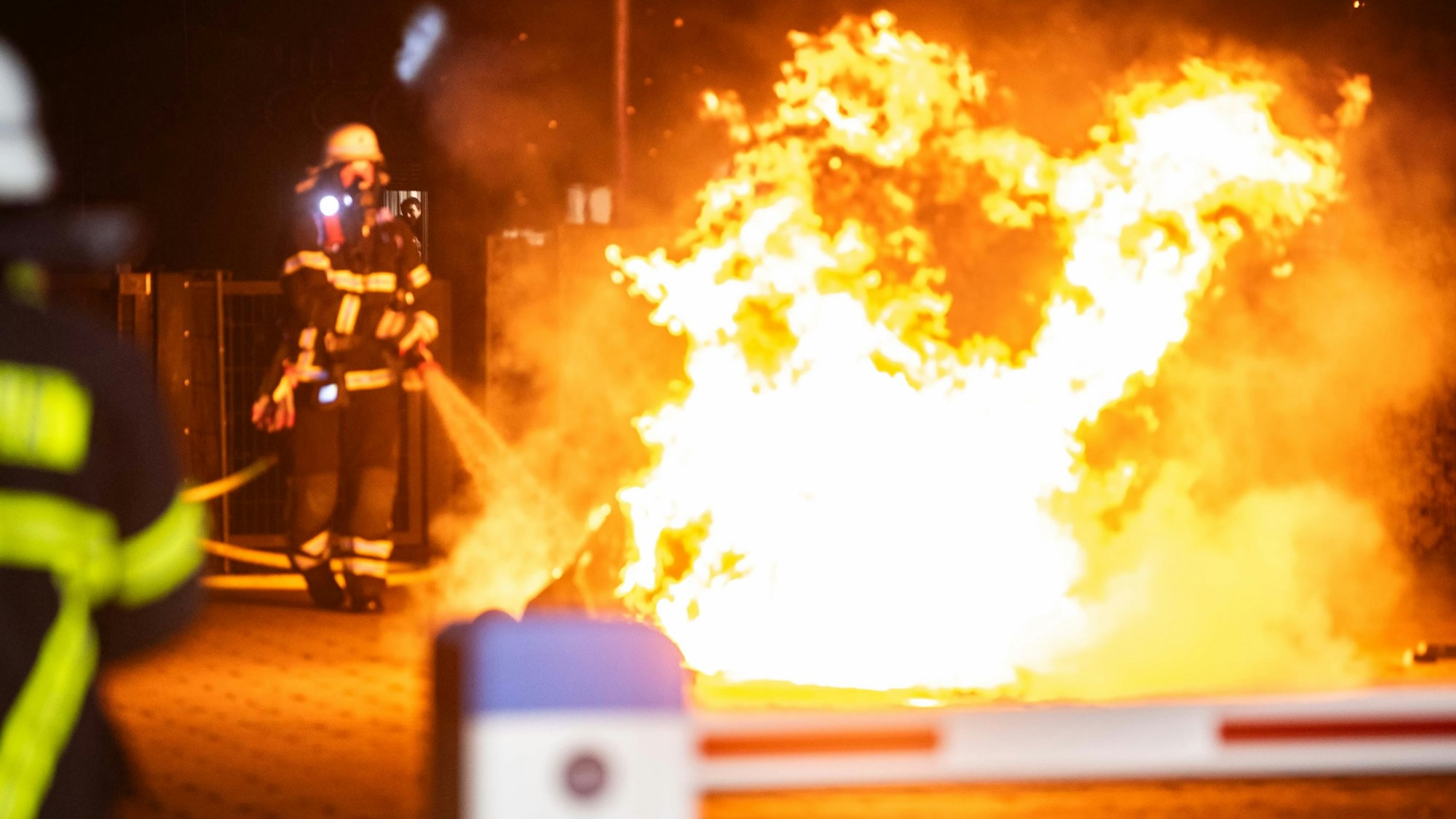 Die Feuerwehr gibt mit einem Feuerwehrschlauch Wasser auf ein Feuer ab.