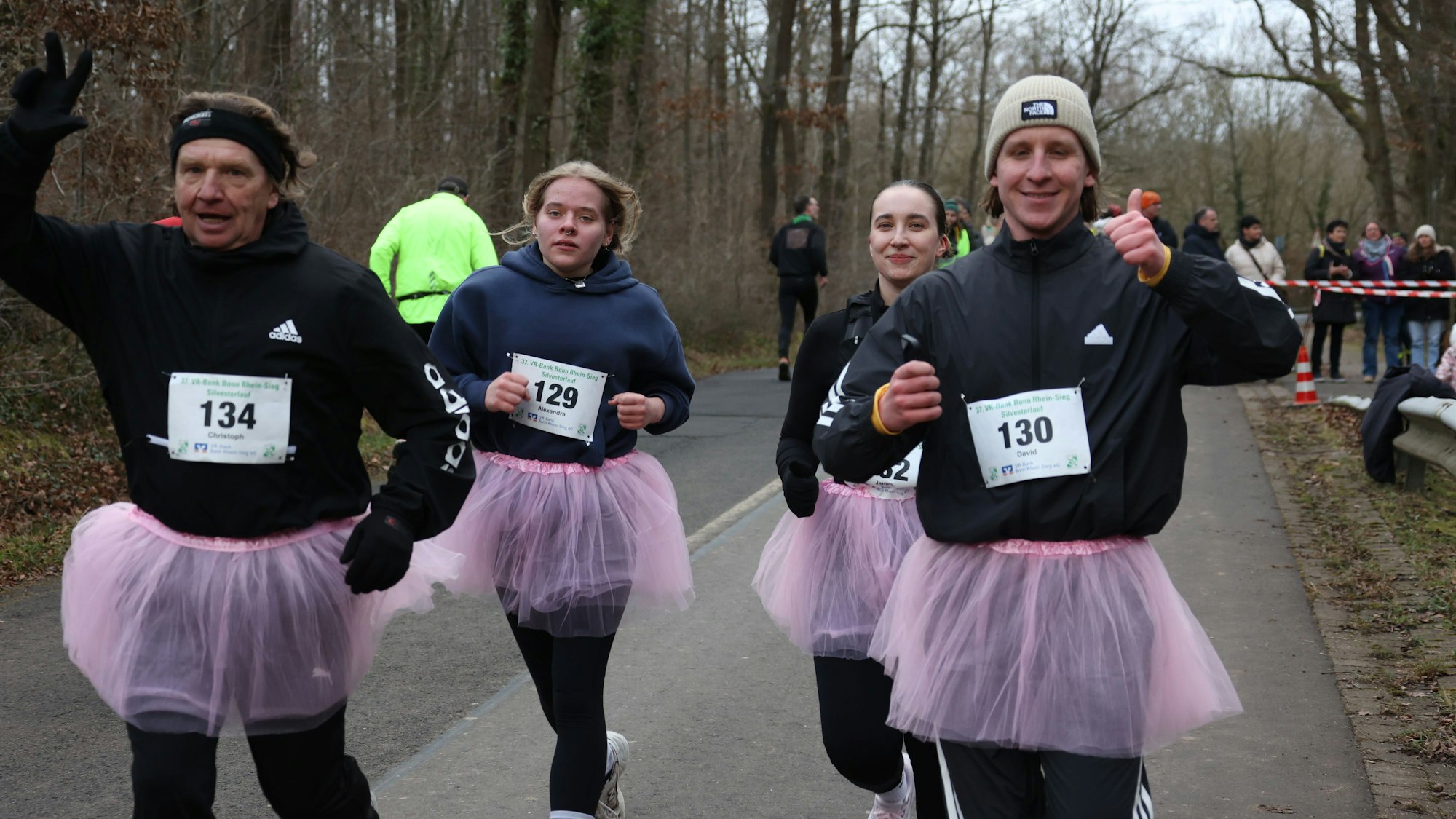 Eine vierköpfige Familie tritt beim Silvesterlauf  in rosa Tütüs an. Die Mutter zeigt den erhobenen Daumen, der Vater macht das Victory-Zeichen.