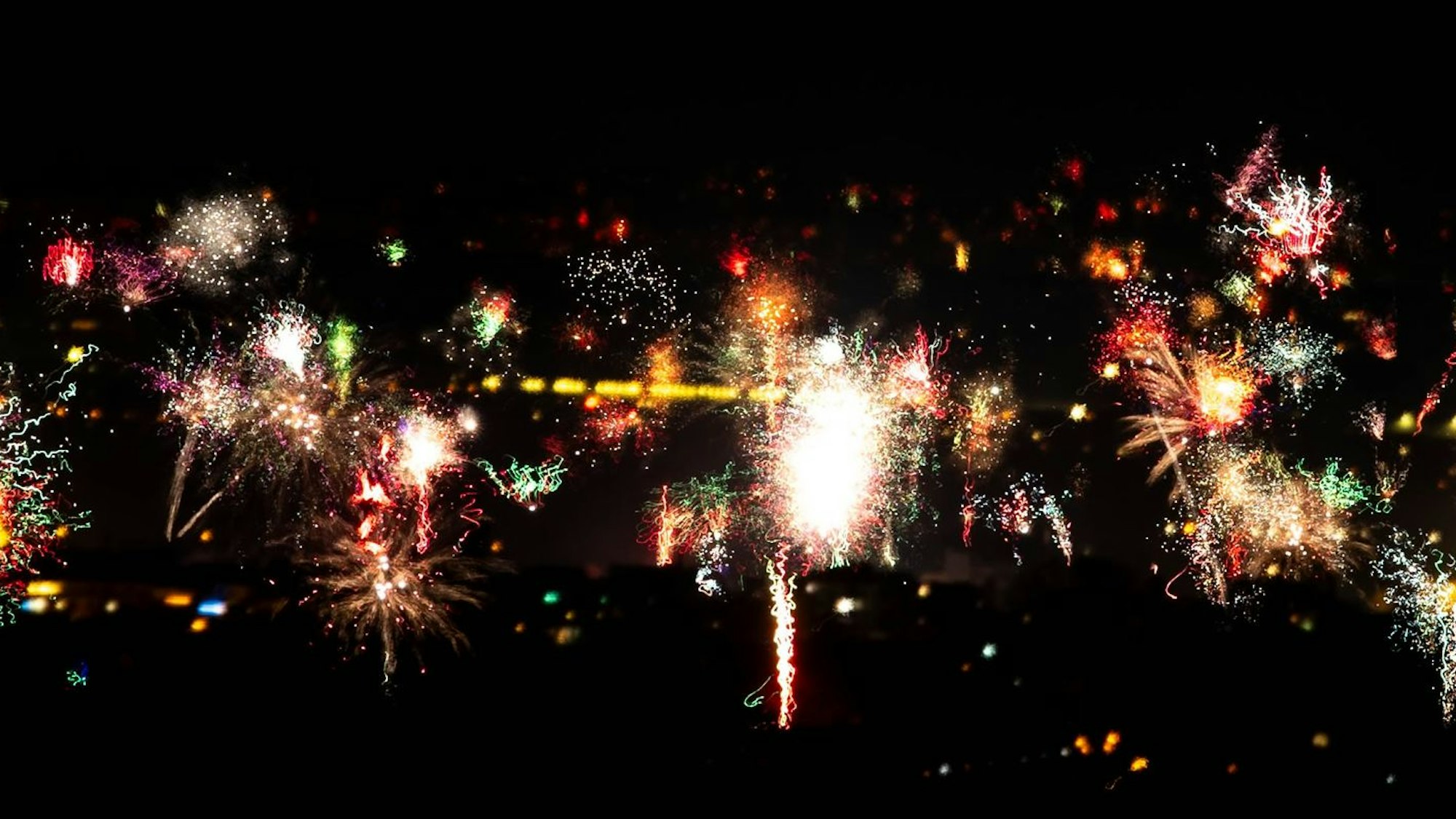 Am dunklen Nachthimmel sieht man buntes Feuerwerk.