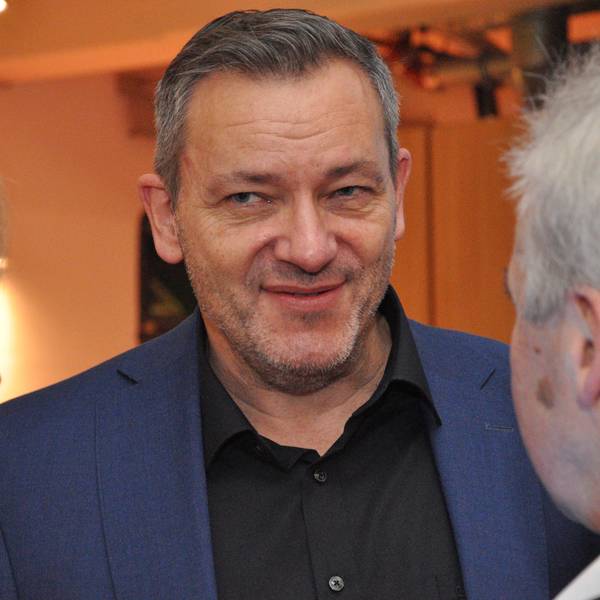 Das Bild zeigt einen Mann in der Mitte, dem eine Frau und ein Mann interessiert zu hören.