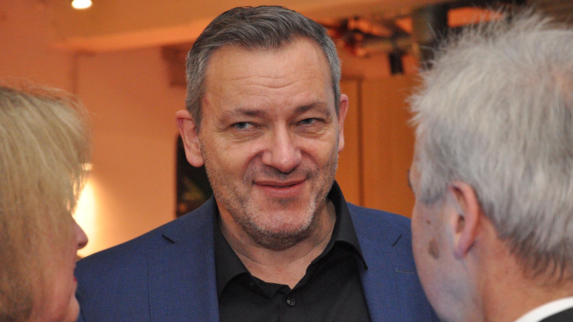 Das Bild zeigt einen Mann in der Mitte, dem eine Frau und ein Mann interessiert zu hören.