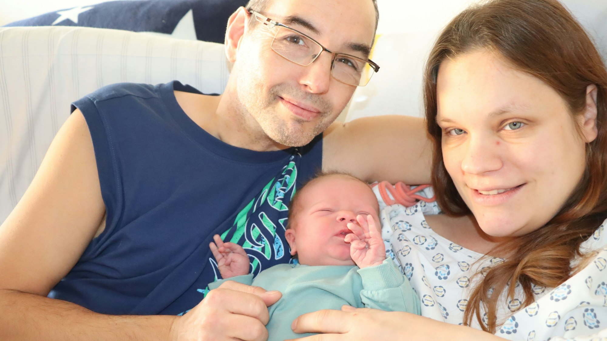 Auf dem Bild sind Eltern mit ihrem neu geborenen Sohn zu sehen.