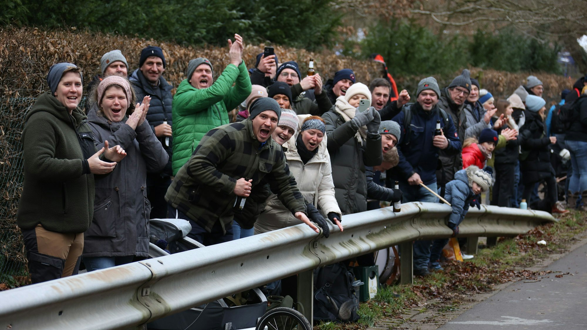 Hinter einer Leitplanke stehen viele Besucher, die die Läufer anfeuern.