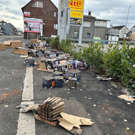 Vor einem Supermarkt an der Hauptstraße in Spich stapeln sich am Neujahrsmorgen Berge aus Feuerwerksresten.
