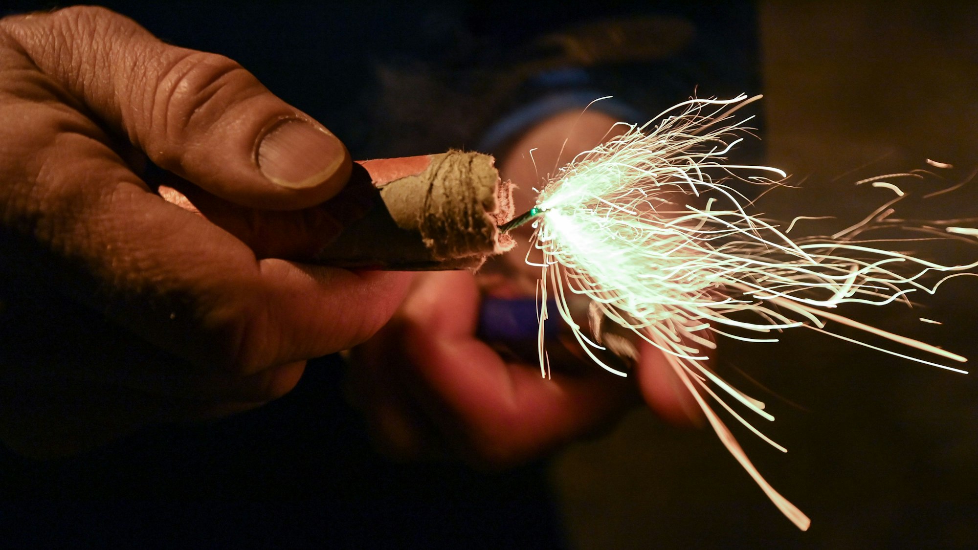 Ein Mann zündet einen Böller am Silvesterabend an.
