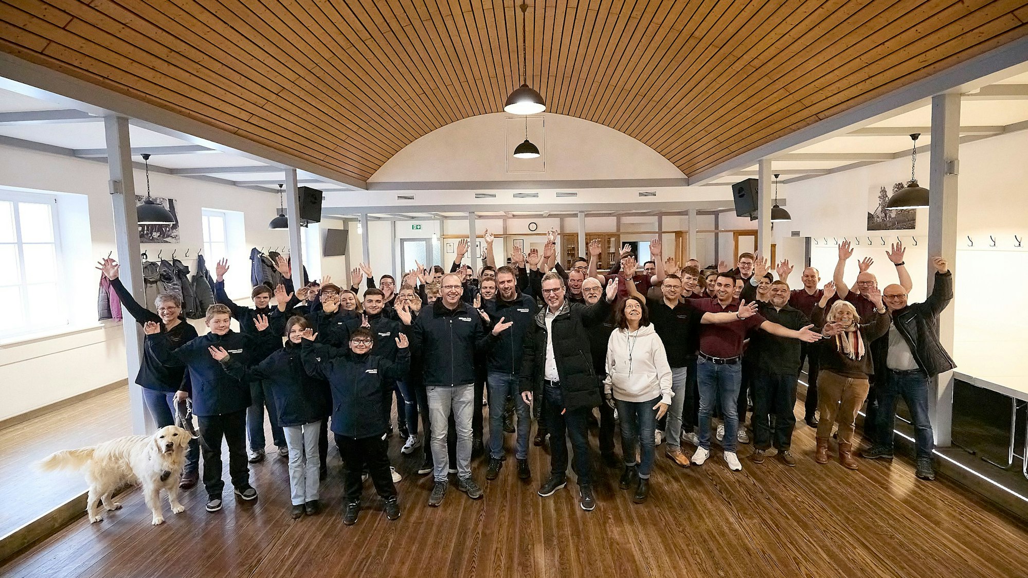 Eine große Gruppe Menschen steht im frisch renovierten Saal.