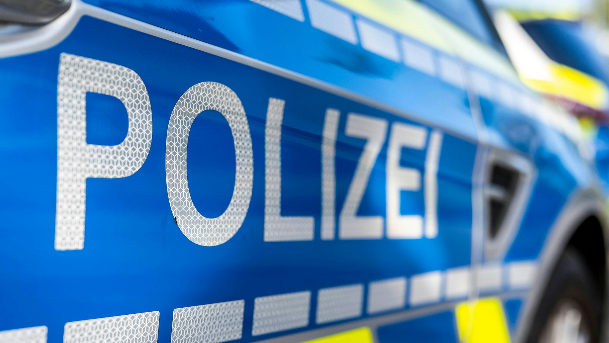 An der Tür von einem Streifenwagen steht der Schriftzug „Polizei“.