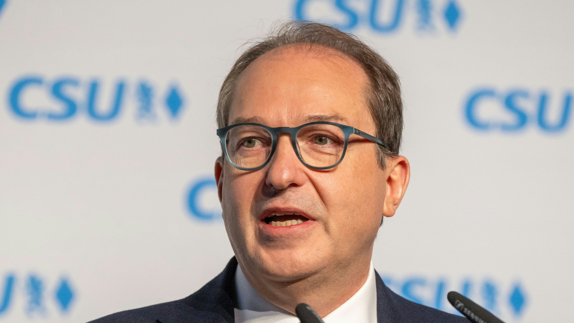 Alexander Dobrindt bei einer Pressekonferenz vor einer Wand mit CSU-Logos.
