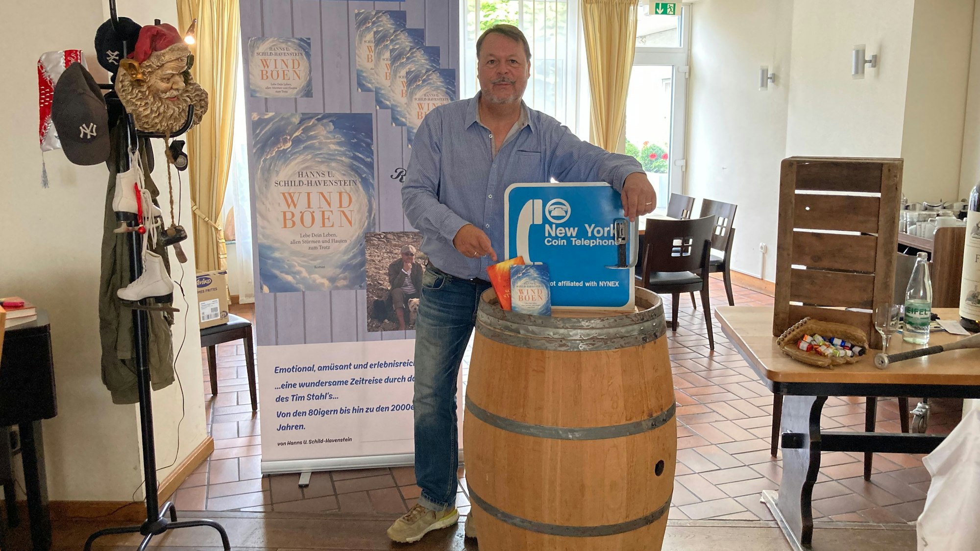 Hanns Udo Schild-Havenstein hat seine beiden Bücher und ein Schild aus Amerika auf einem Weinfass drapiert.