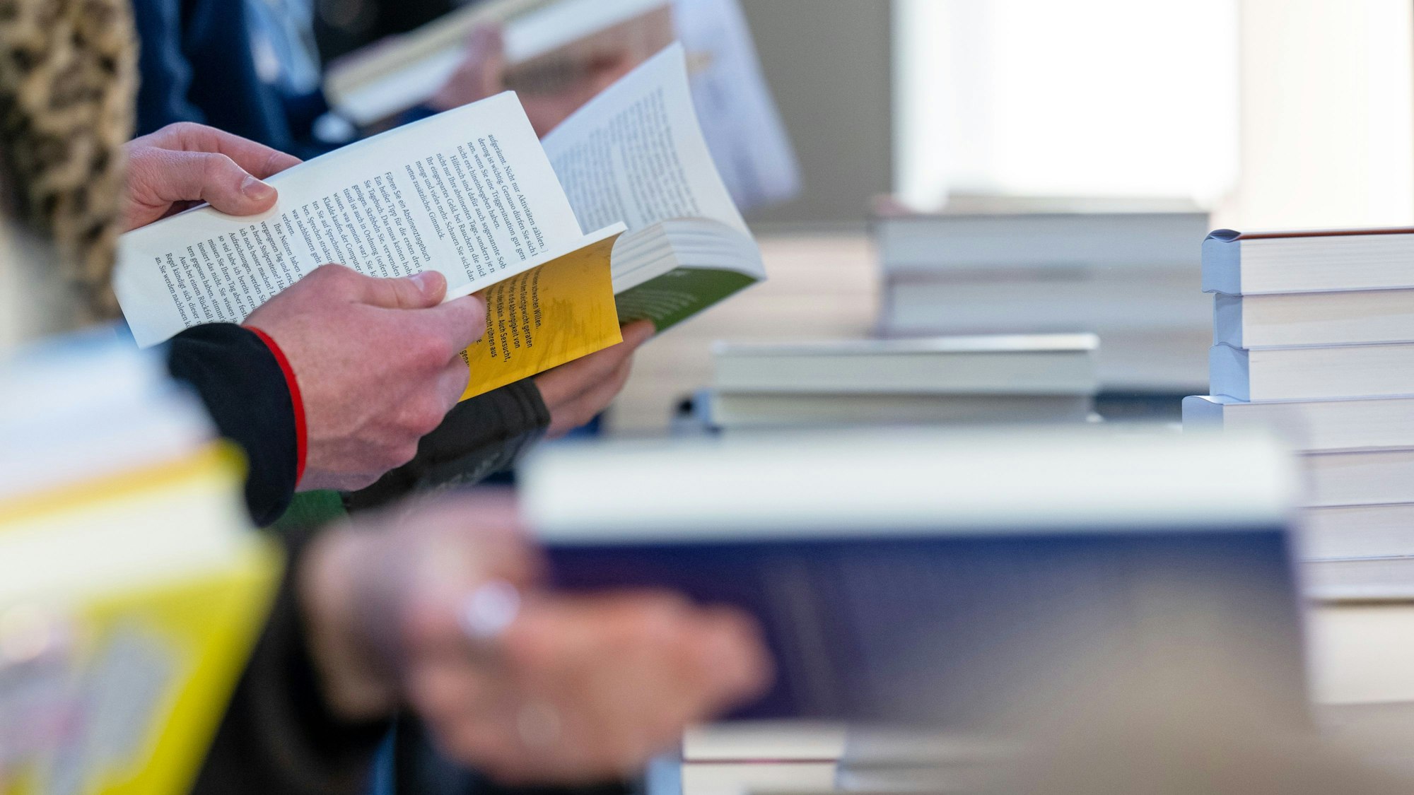 Besucher der Leipziger Buchmesse lesen am Stand eines Verlages.