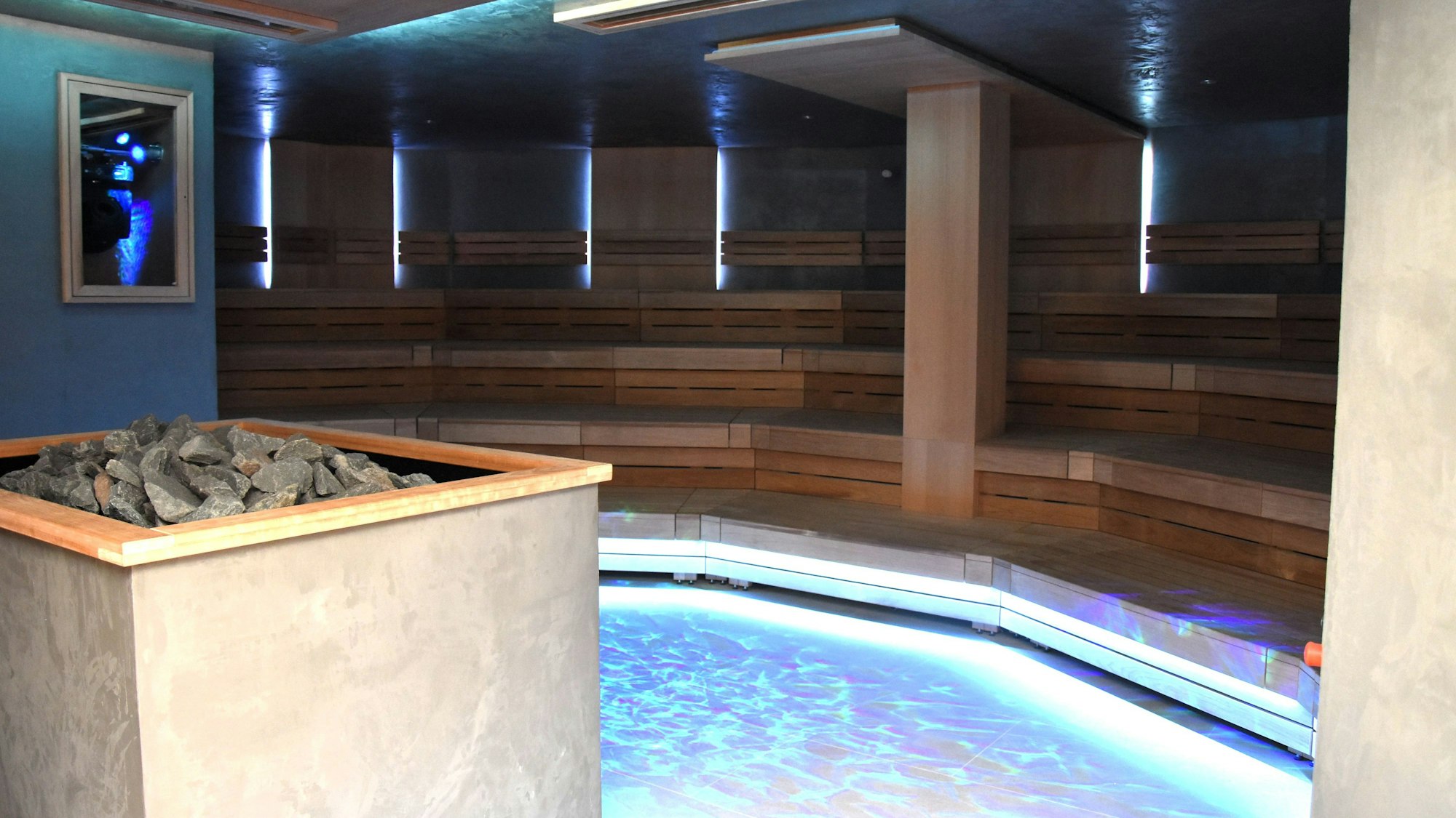 Saunaliegen hinter einem blau schimmernden Pool.