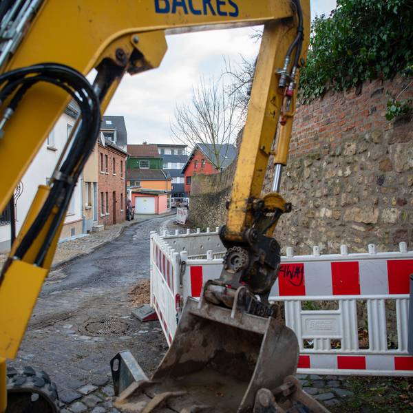 Hinter einer gelben Baggerschaufel ist die Brauersgasse zu sehen, an der bereits Warnbaken aufgestellt wurden.