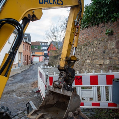 Hinter einer gelben Baggerschaufel ist die Brauersgasse zu sehen, an der bereits Warnbaken aufgestellt wurden.