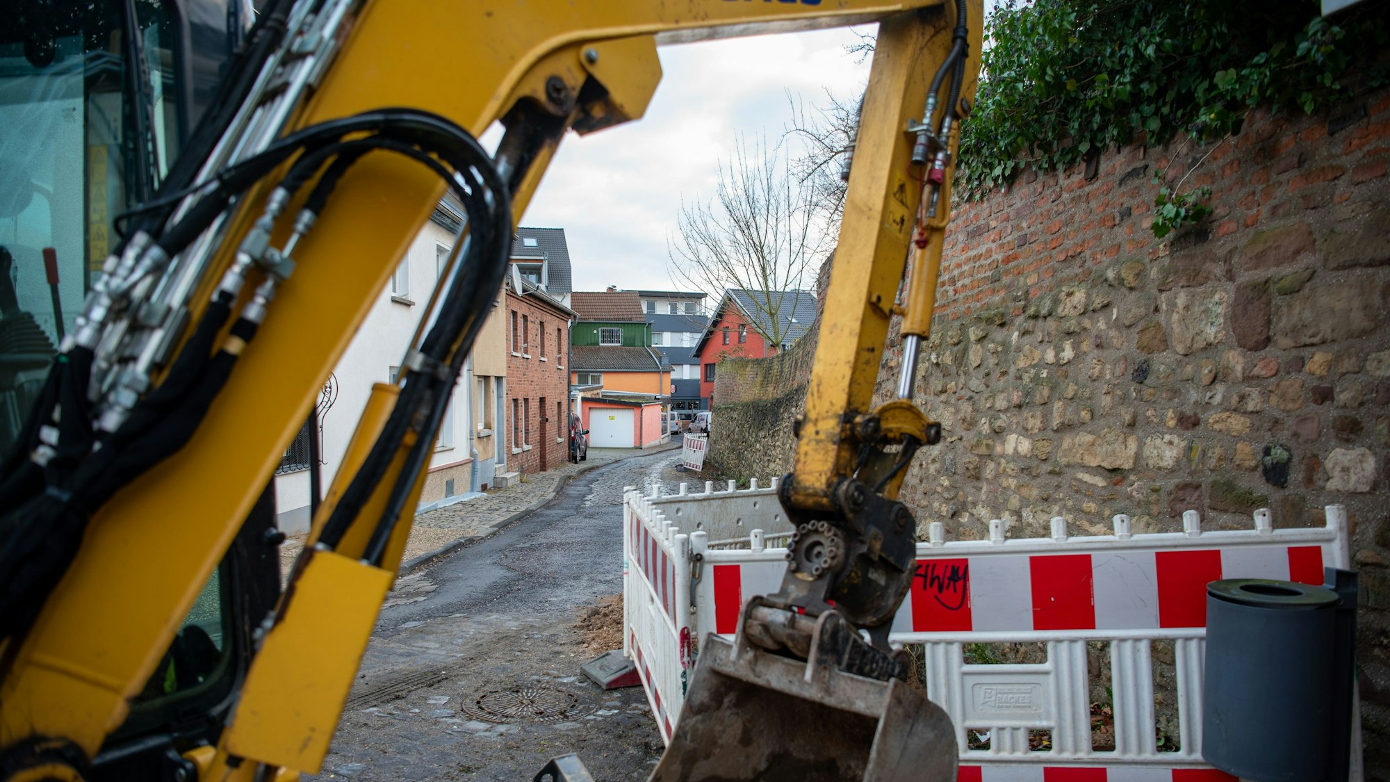 Hinter einer gelben Baggerschaufel ist die Brauersgasse zu sehen, an der bereits Warnbaken aufgestellt wurden.