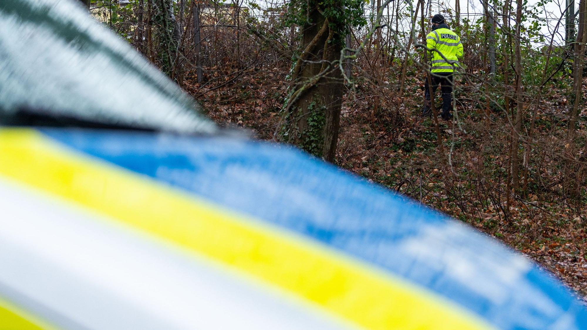Ein Polizist sucht in einem Wald nach Spuren (Symbolfoto).