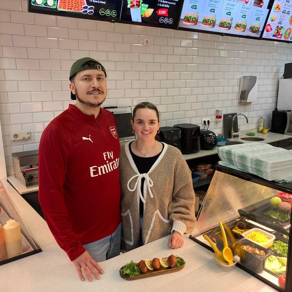 Ein Mann mit Kappe und eine Frau stehen hinter einer Theke, auf der İçli köfte angerichtet wurden.